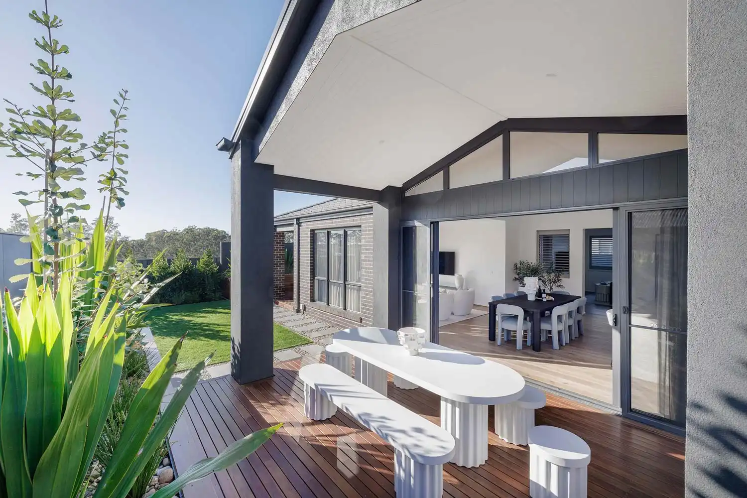sliding doors to alfresco timber decking with white crisp furniture to bright up the backyard