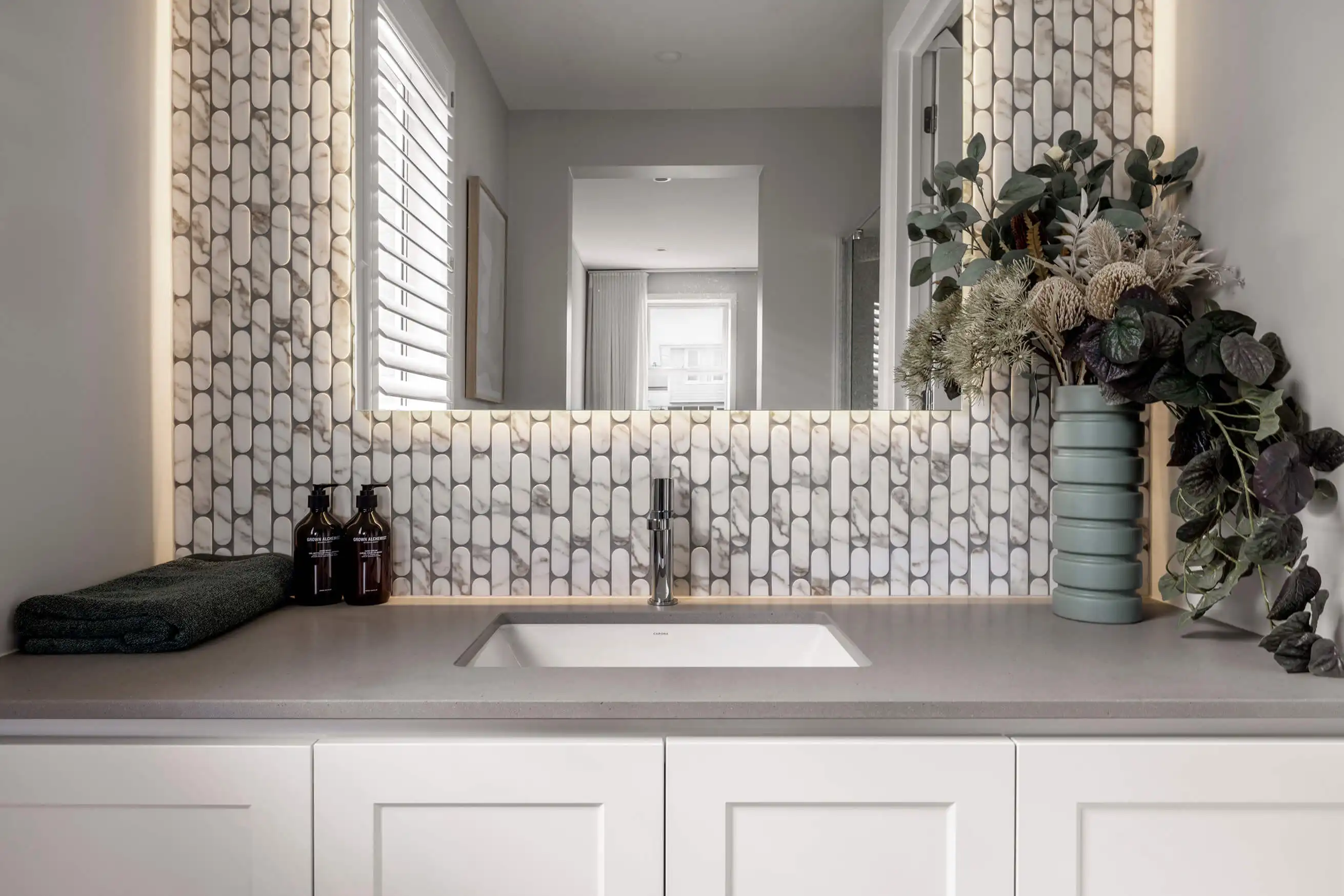 Photo of a bathroom basin with marble textured mosaic tiling around the mirror in the Simonds Tallowood 52 home design