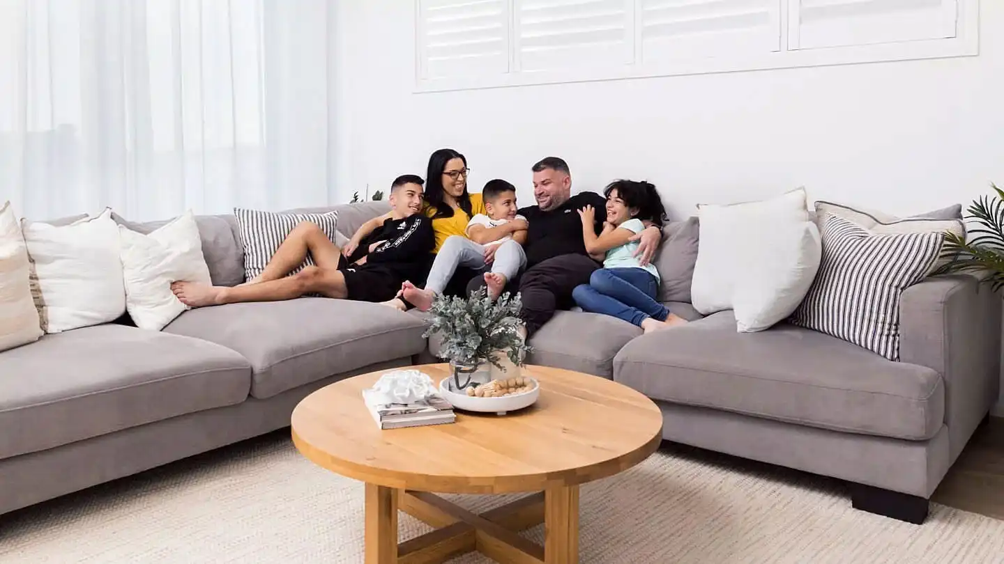 A photograph of a family seated on a couch in their living room area.