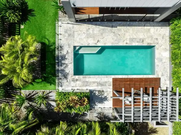 birds eye view of a Simonds display home in queensland with a pool and stoned tiles surrounded with lush gardens and pergola decking