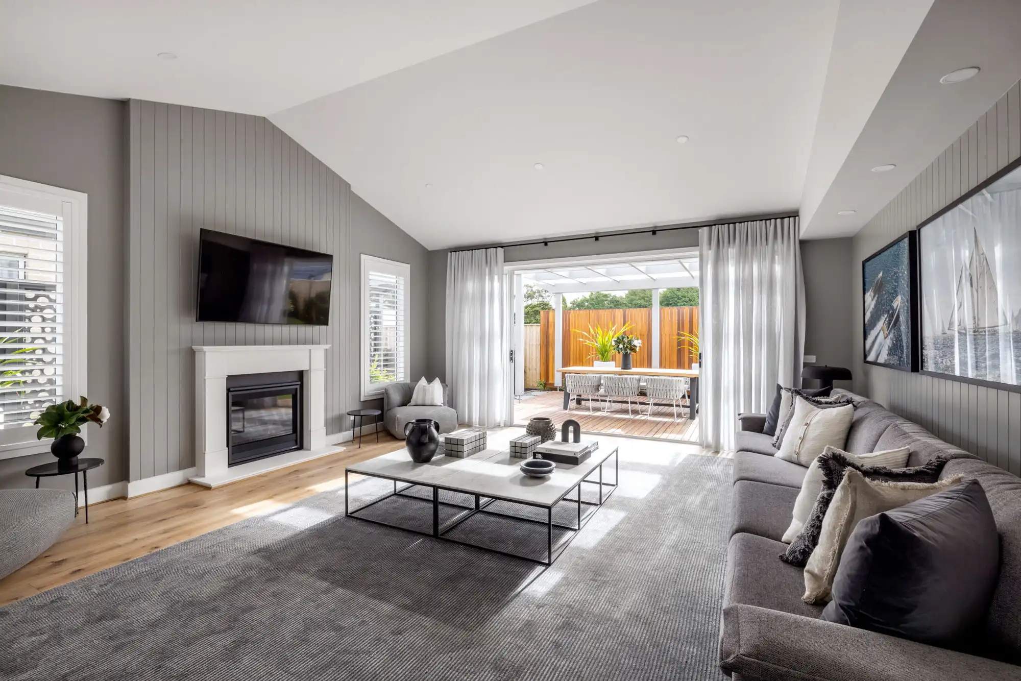 Country-style home with a raked ceiling and paneled feature wall around the fireplace with grey neutral tones throughout the akuna 29
