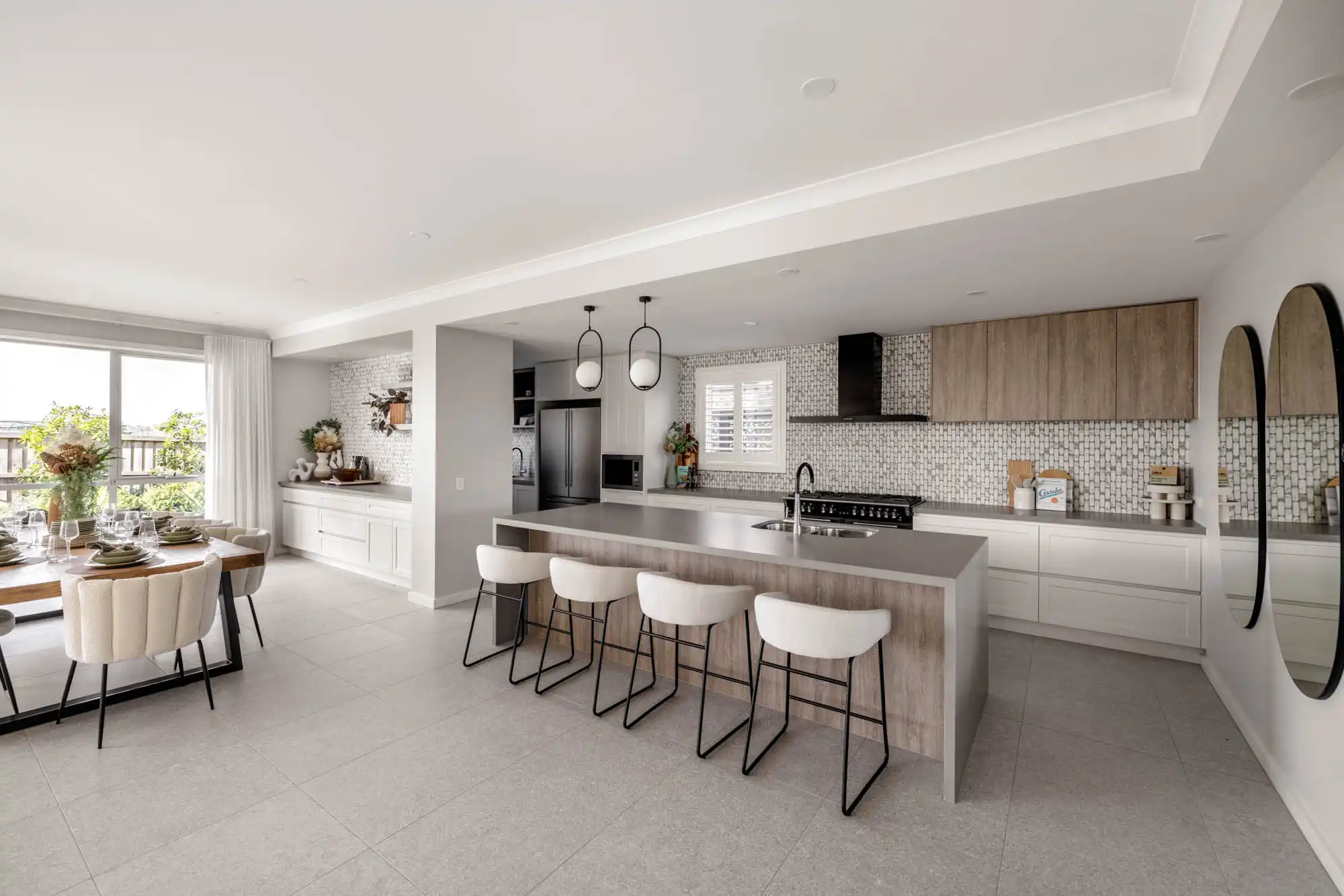 contemporary coastal-style kitchen and dining space with patterned splash back and timber cabinetry