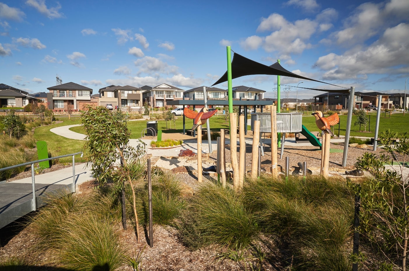 Photo of a playground surrounded by plants and in the distance, newly built double storey house designs in Meridian Estate of Clyde North